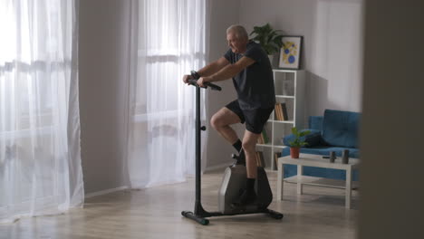 stationary-bicycle-for-home-sport-equipment-for-caring-health-adult-man-is-training-alone-in-living-room-fitness-and-sport-activities